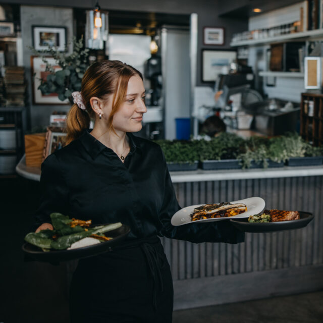 Waitress carrying tray of plates