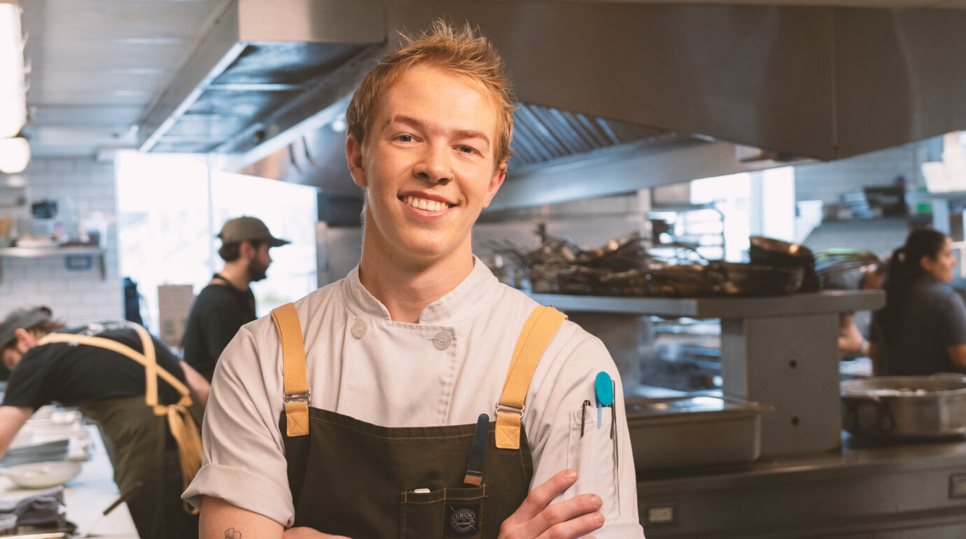 Restaurant ambassador, Owen, smiling for headshot in kitchen